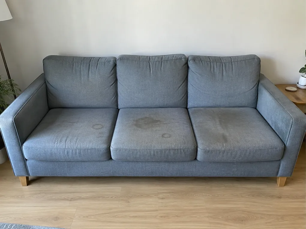 Illustrative before view: blue-grey straight sofa with stained seats